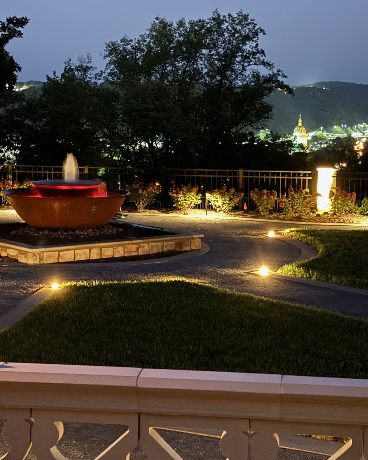 A lit path and copper fountain at dusk on a residential property, with the valley beyond