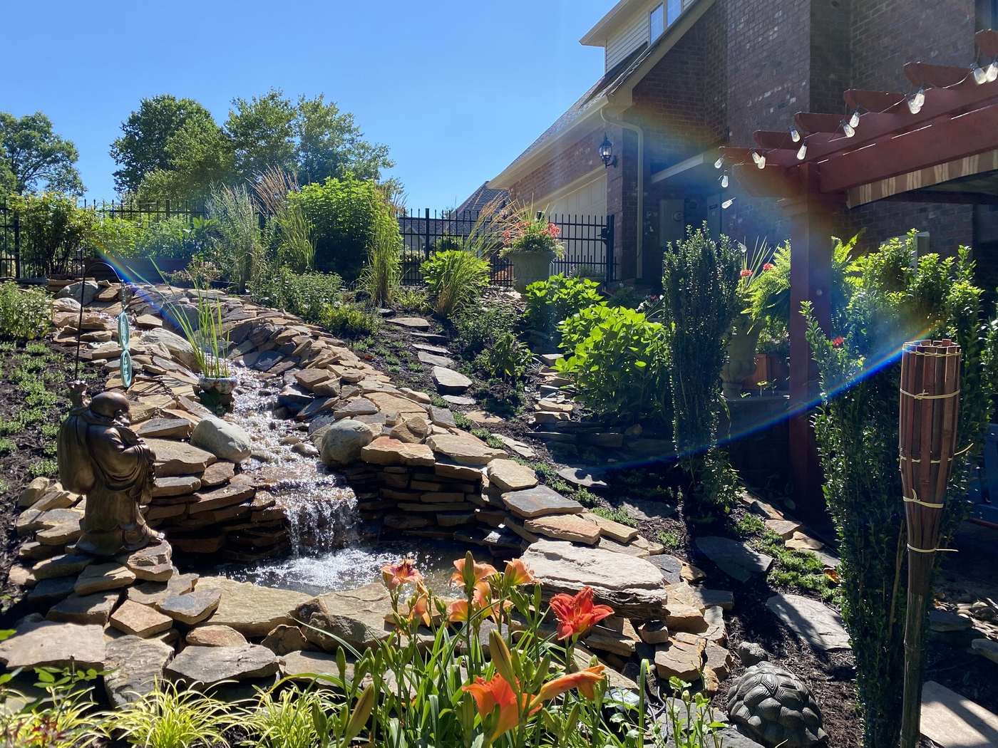 A flagstone water feature and planted beds beside a residential terrace
