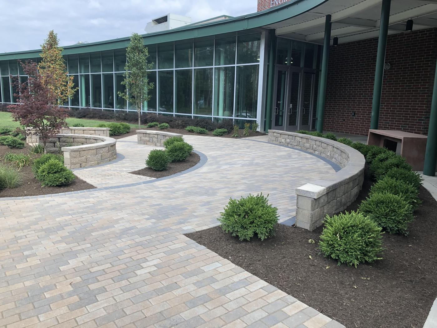 Paver plaza, curved seat walls and new plantings at an institutional building