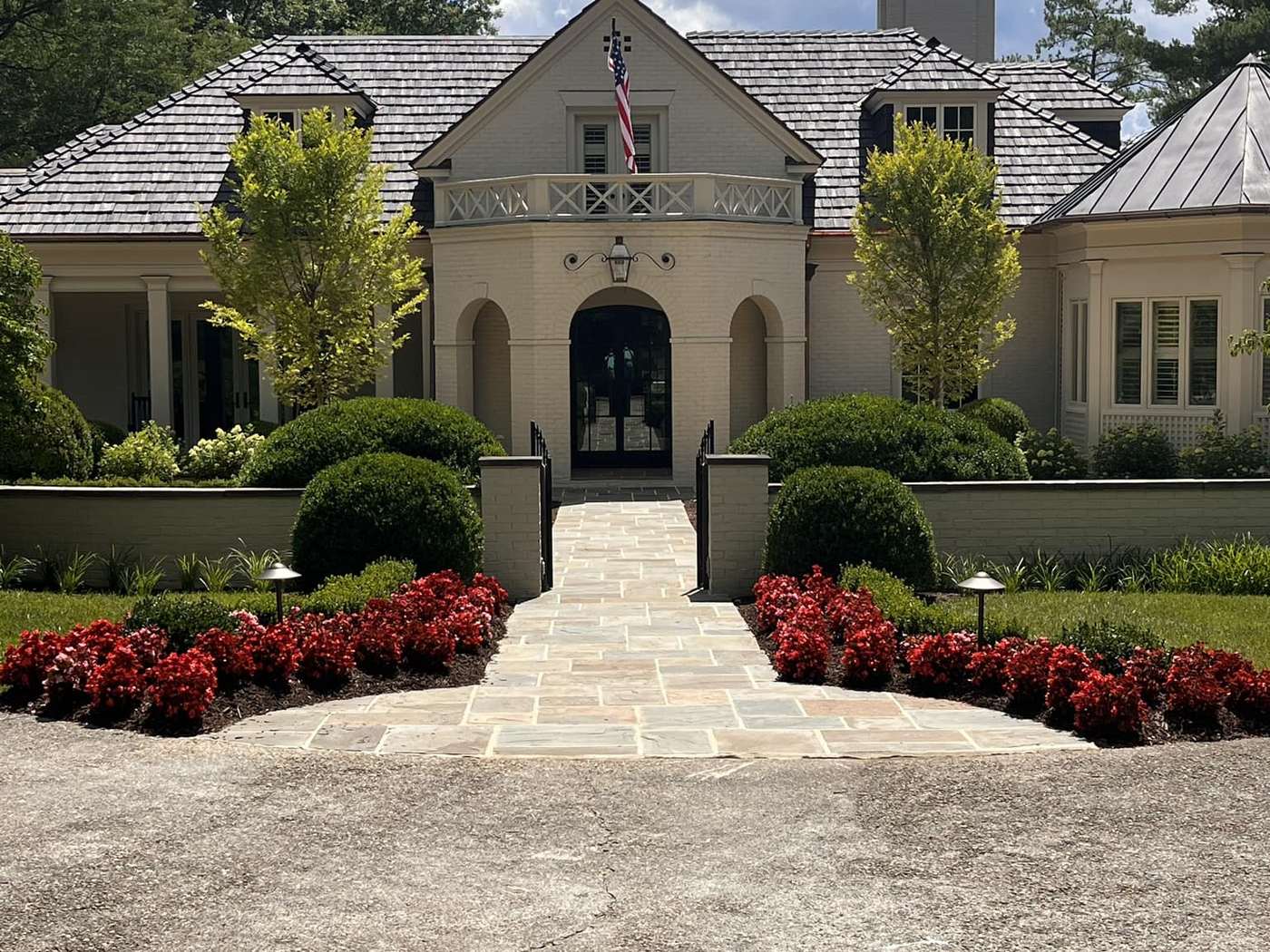 Flagstone walk, clipped hedging and red azaleas framing a residence entrance