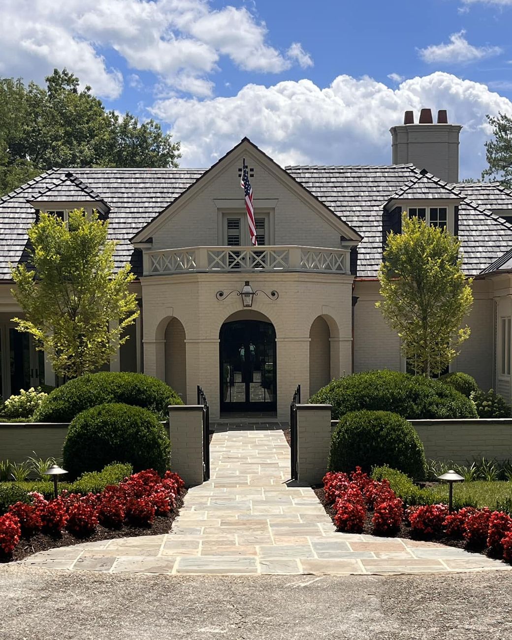 Flagstone entry walk with red begonias, rounded boxwood and landscape lighting at a White Sulphur Springs residence