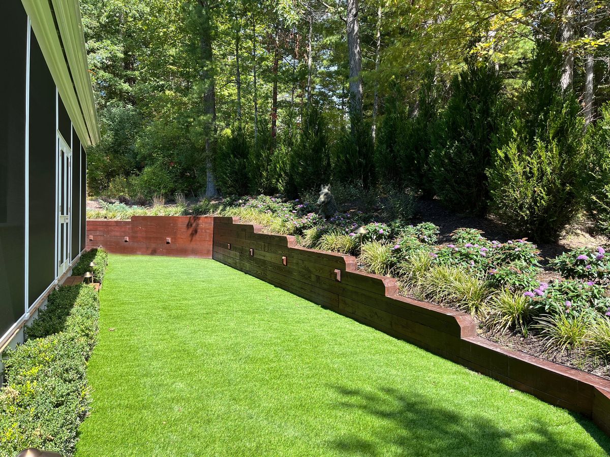 Timber retaining wall with lit planting beds above a turf side yard at a White Sulphur Springs home