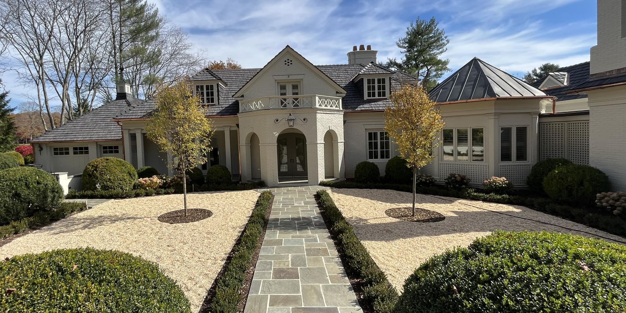 Bluestone walk between clipped boxwood and gravel courtyard beds at a home in White Sulphur Springs, West Virginia